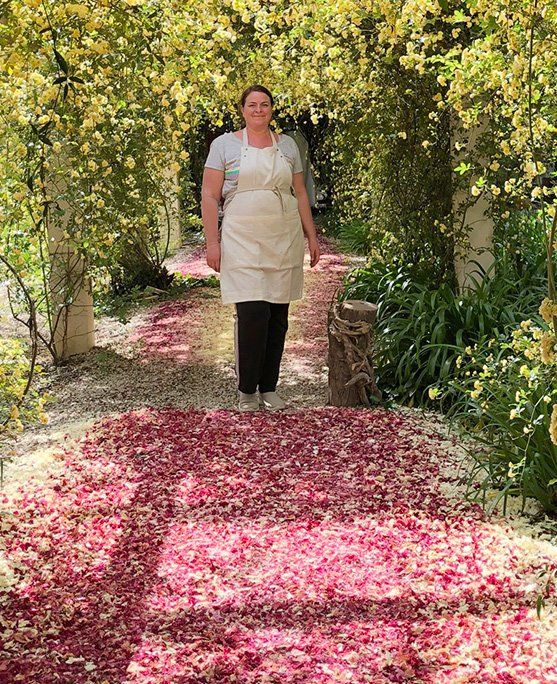 Productrice debout dans une allée fleurie de la ferme Pétales de Provence