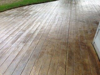 Stamped concrete patio with a wood plank design, tan and brown hues.