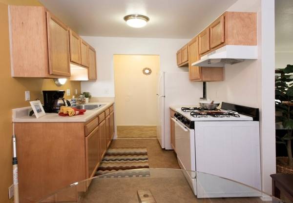 A kitchen with wooden cabinets and a white stove
