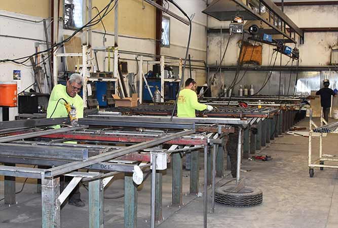 Men working on metal frames in a manufacturing workshop.