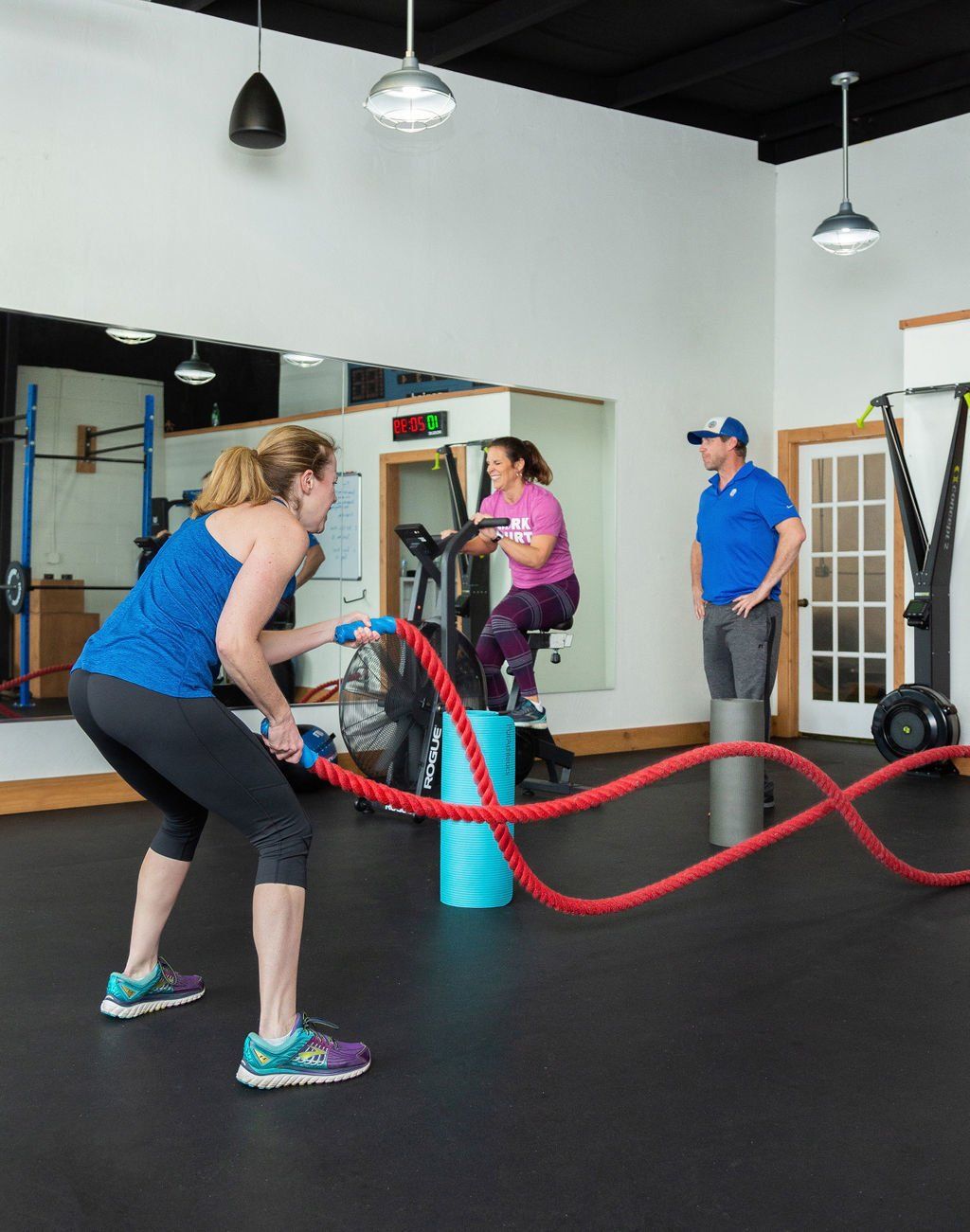 A group of people are doing exercises with ropes in a gym