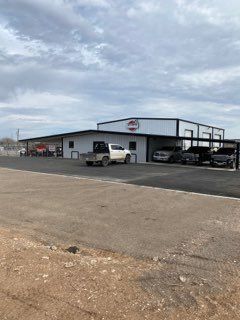 Industrial building with parked vans and trucks under a cloudy sky