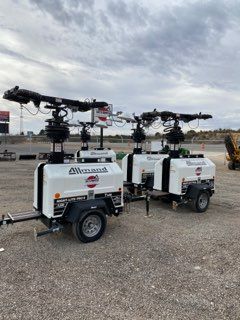 Two white drone ground stations with mounted quadcopters parked on gravel outdoors