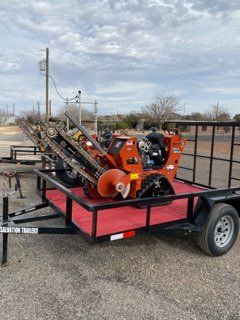 Orange pipe-cleaning machine on a trailer in an outdoor lot under a cloudy sky