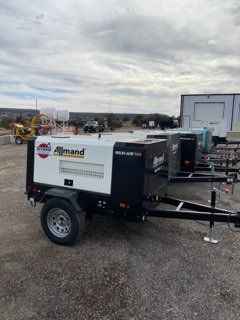 Industrial trailer-mounted Almand generator on gravel lot under cloudy sky