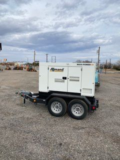 White utility trailer with generator parked on a gravel lot under cloudy sky