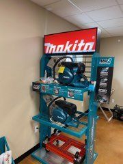 Makita power saw display on teal shelving in a store aisle with red signage