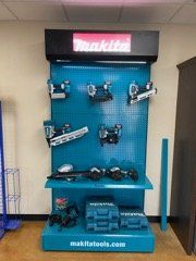 Makita power tools display on a blue pegboard in a store kiosk