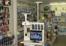 Inside a store, a television is on display, surrounded by electronic parts and devices on shelves.