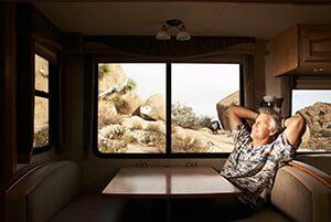Man relaxing in RV, looking out at desert landscape.