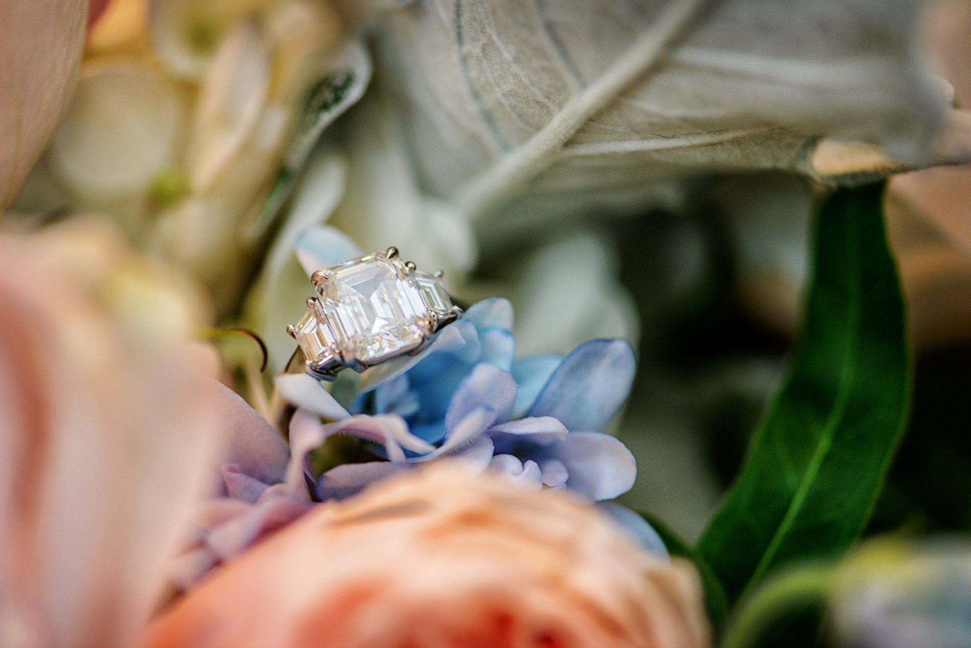 A close up of an engagement ring in a bouquet of flowers.
