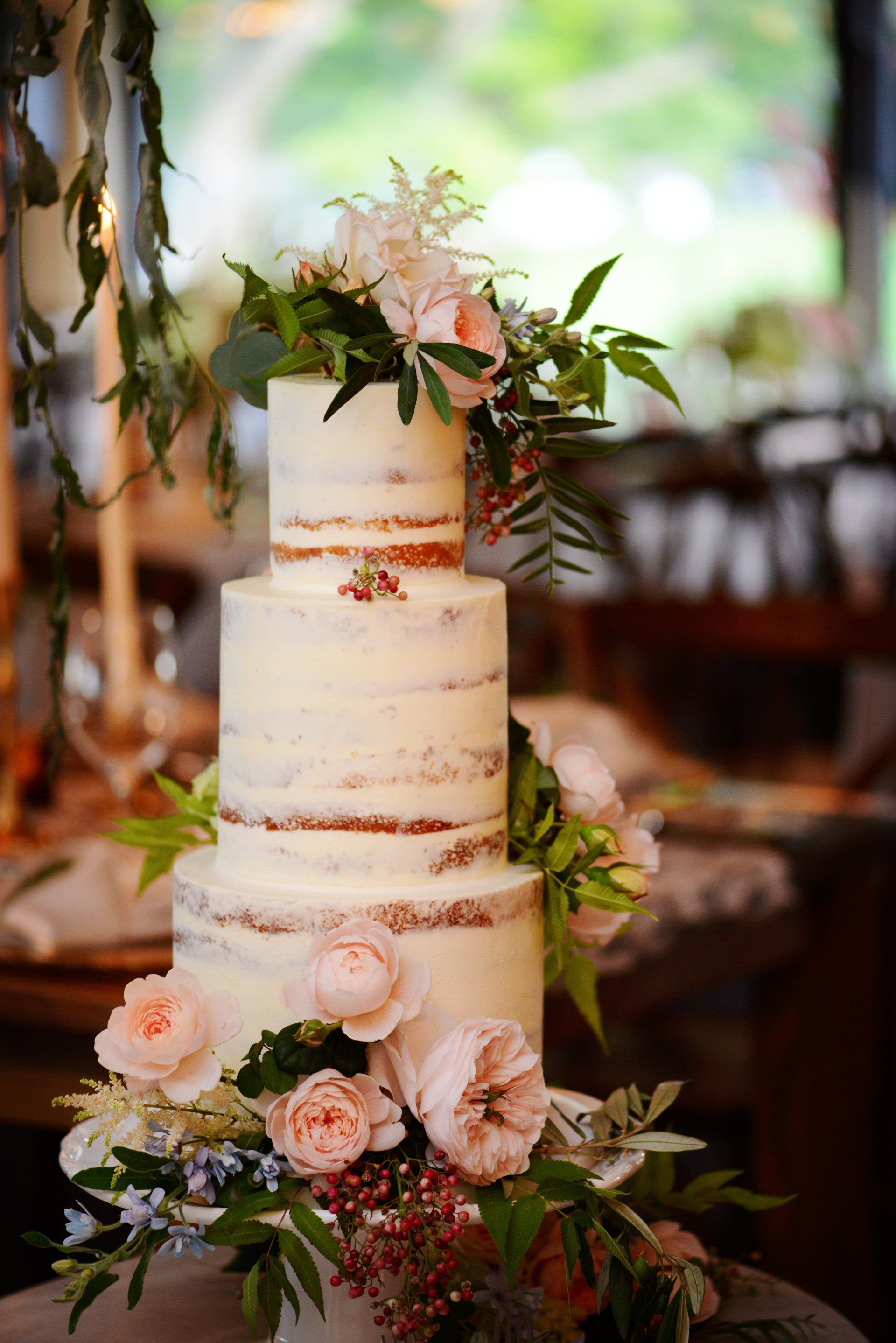 A wedding cake with flowers on top of it is on a table.