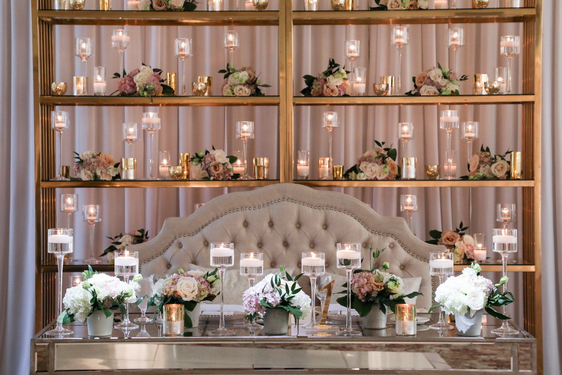 A table with candles and flowers on it in front of a bookshelf.