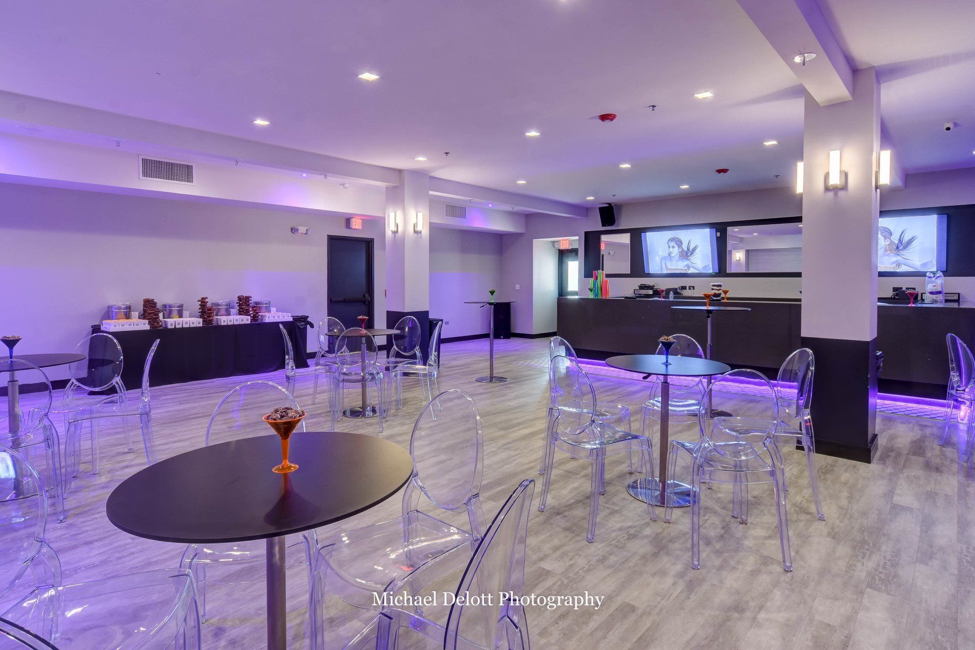 A large room with tables and chairs and purple lights.