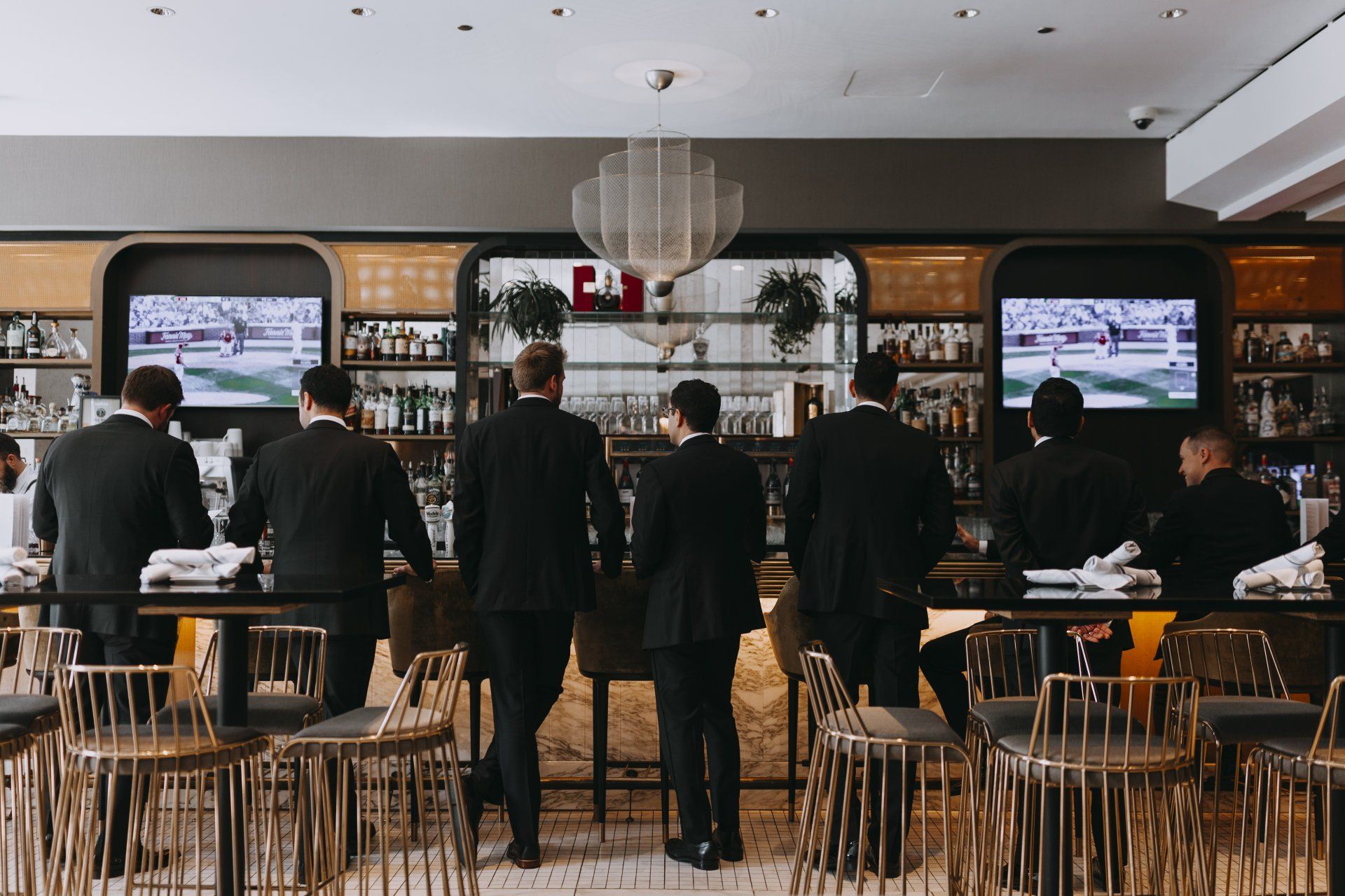 A group of men in suits are standing at a bar.