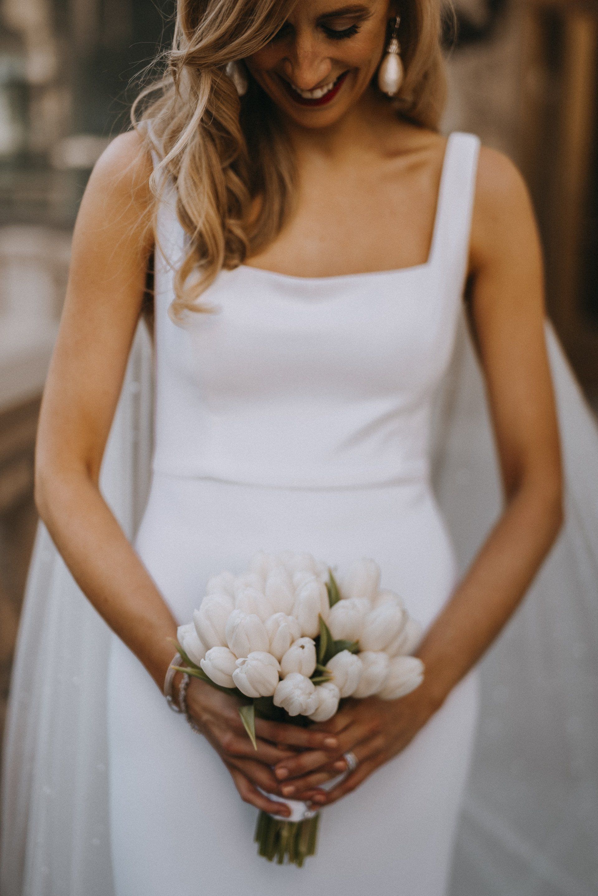 A bride in a white dress is holding a bouquet of white flowers.