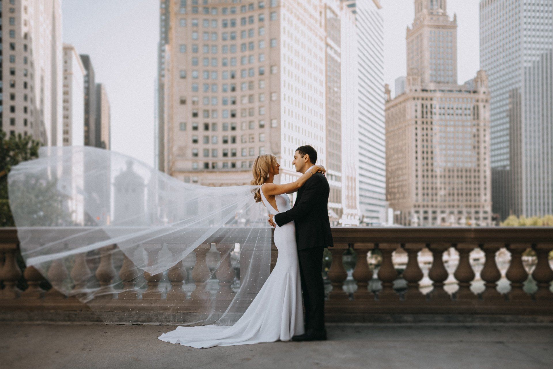 A bride and groom are posing for a picture in front of a city skyline.