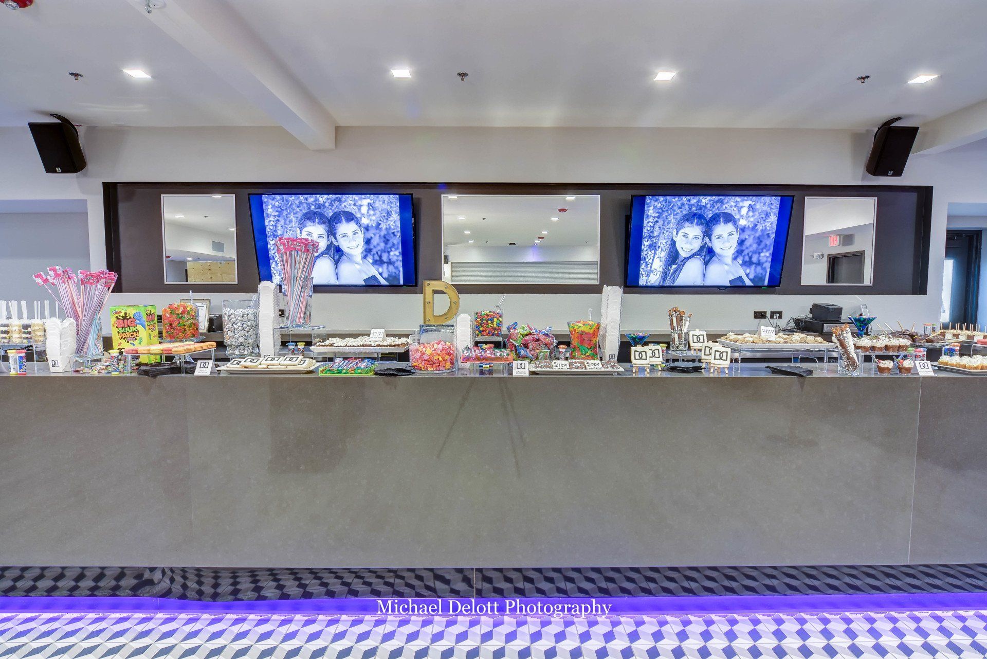 A long counter in a restaurant with two televisions on the wall.
