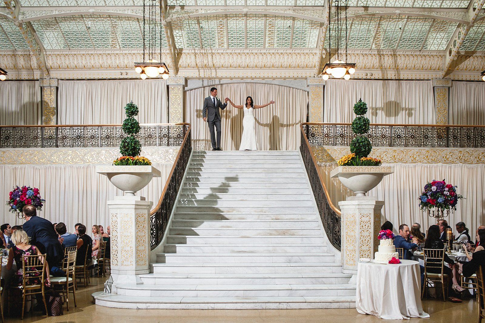 A bride and groom are standing on a set of stairs holding hands.