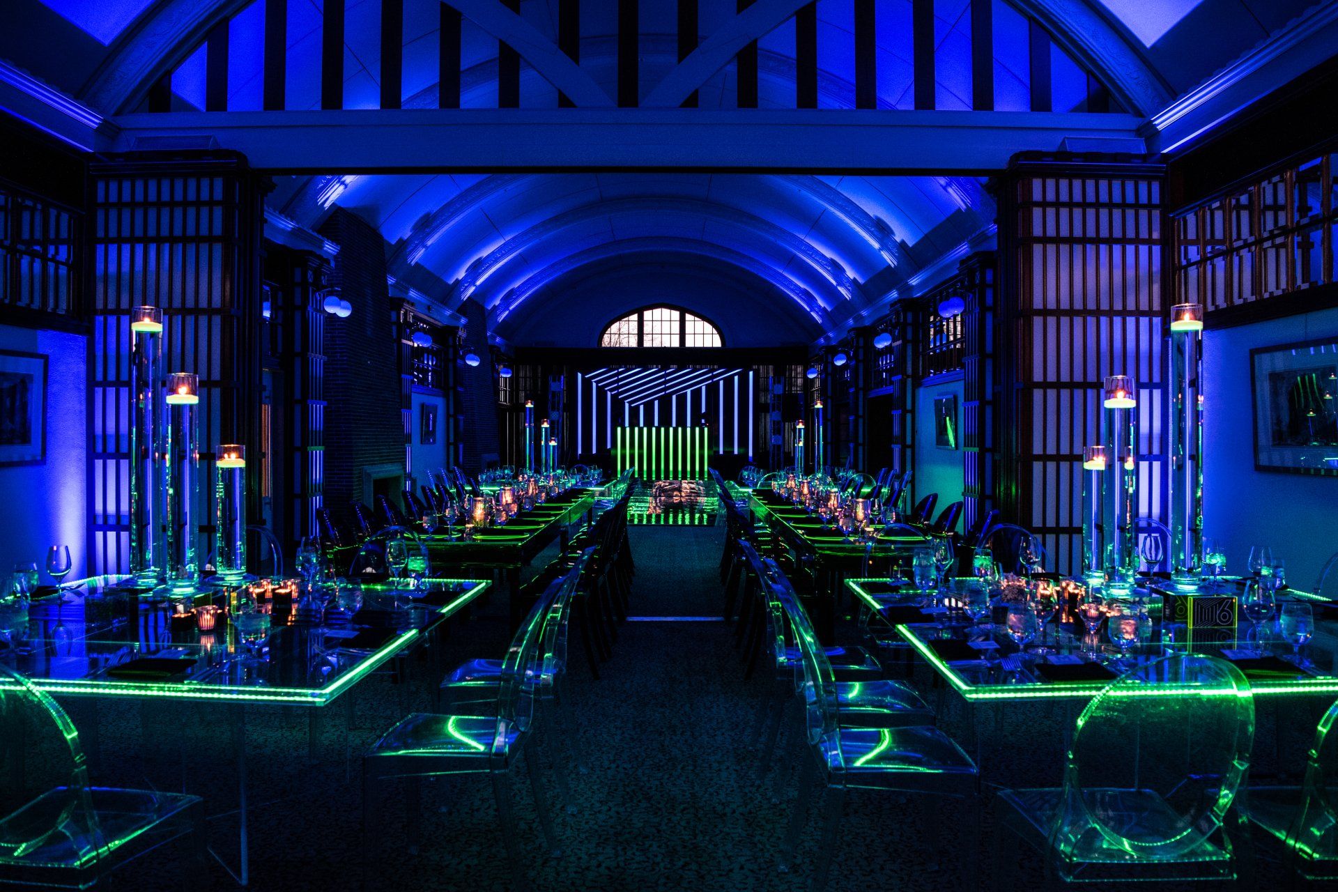 A long room with tables and chairs lit up with blue lights