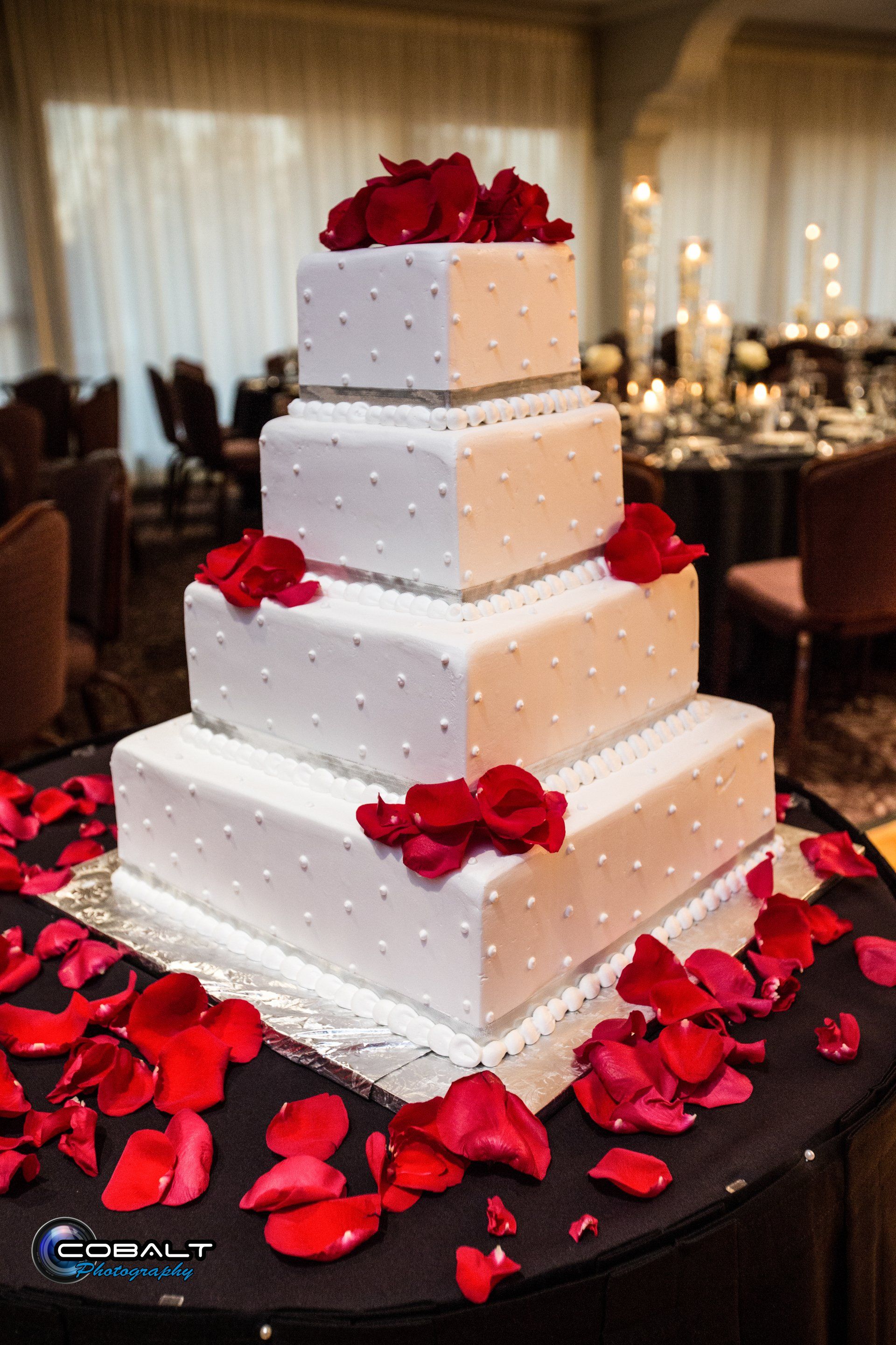 A white wedding cake with red roses on top of it