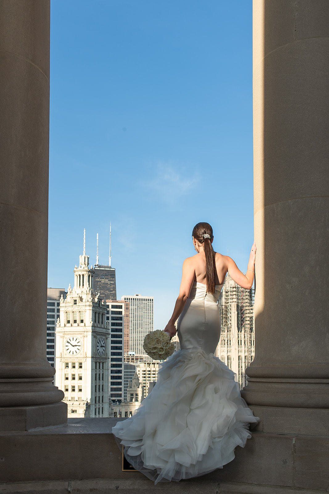 A woman in a wedding dress is standing in front of a clock tower