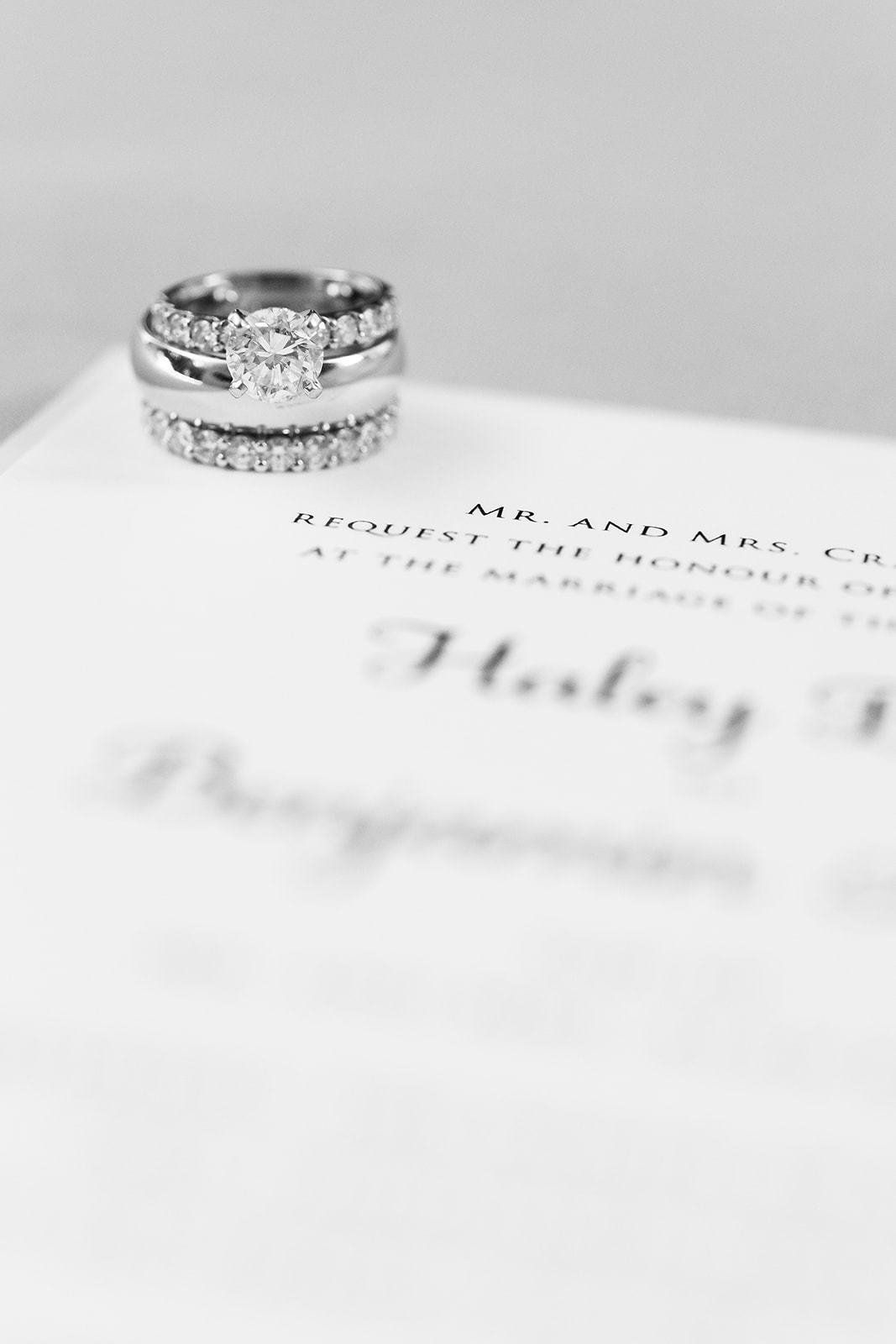 A couple of wedding rings sitting on top of a wedding invitation.