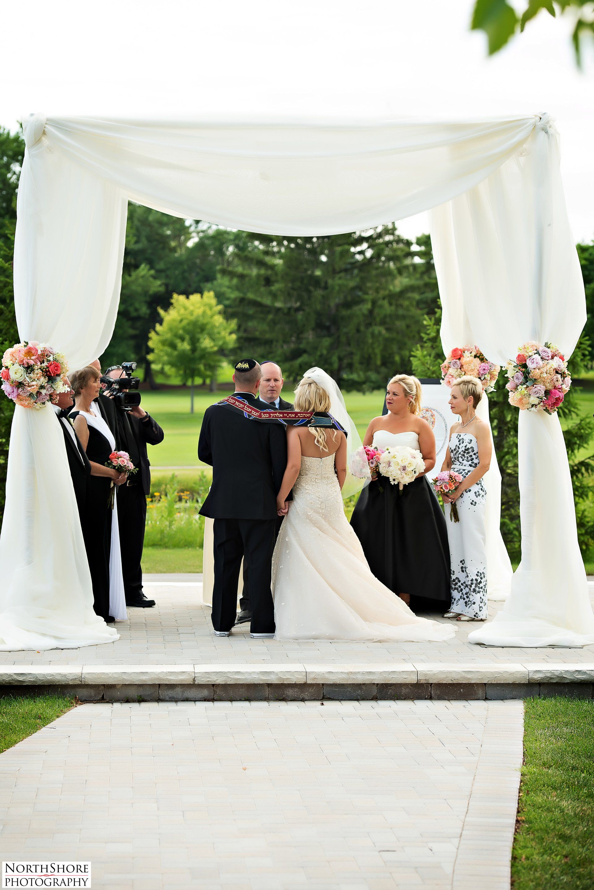 A bride and groom are getting married under a white canopy.