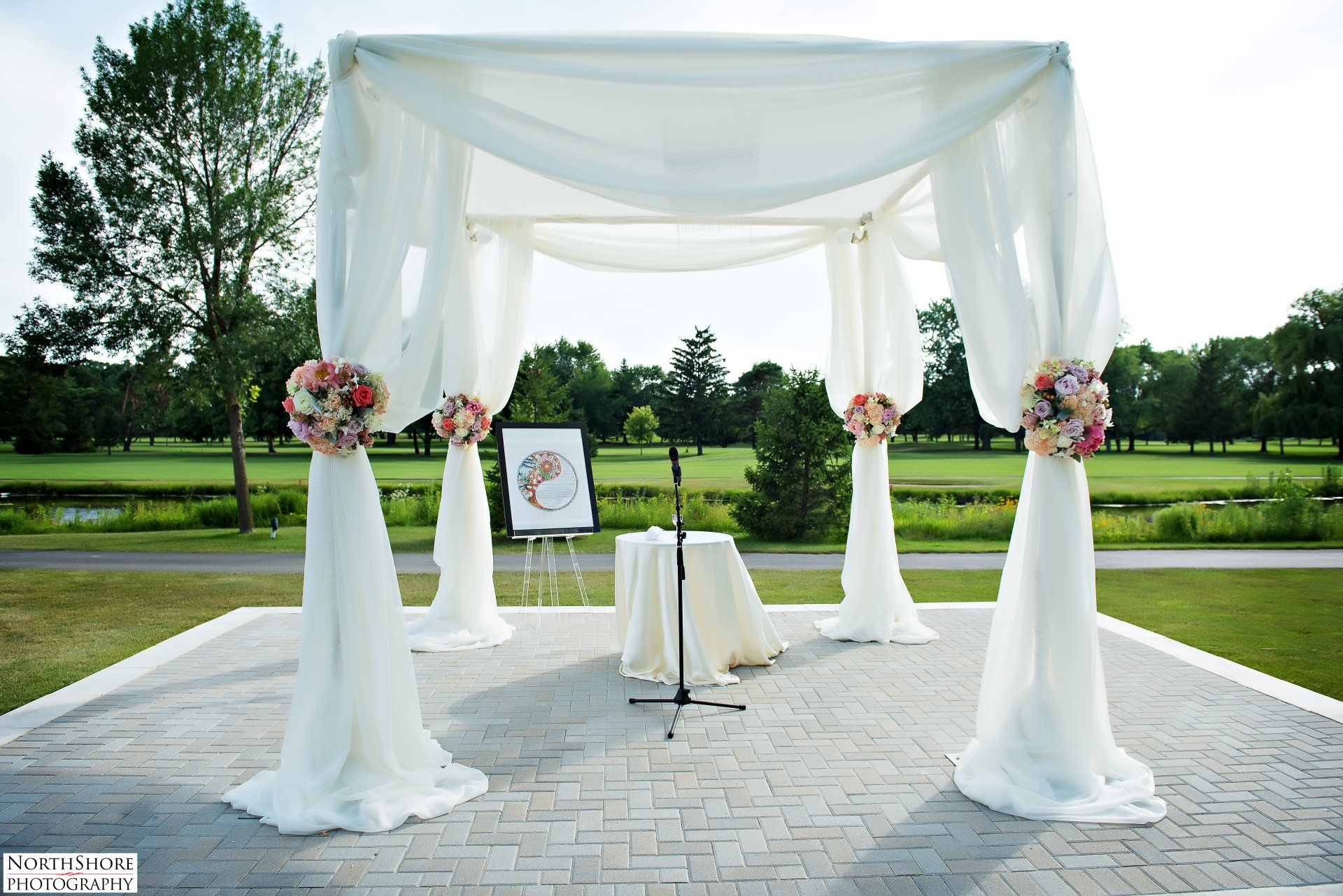 A white canopy with flowers and a table underneath it