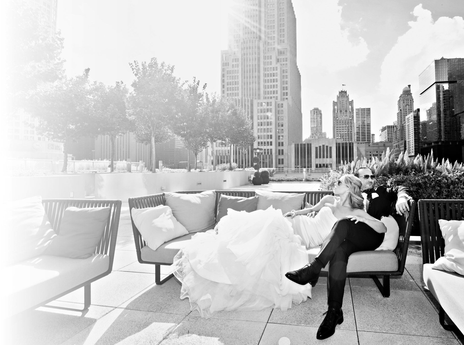 A bride and groom are sitting on a couch in front of a city skyline.