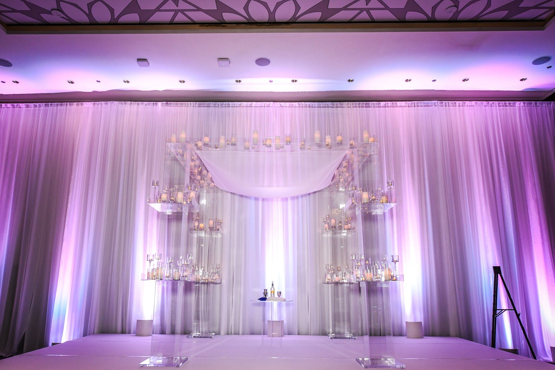 A wedding ceremony is taking place in a room with purple lighting.