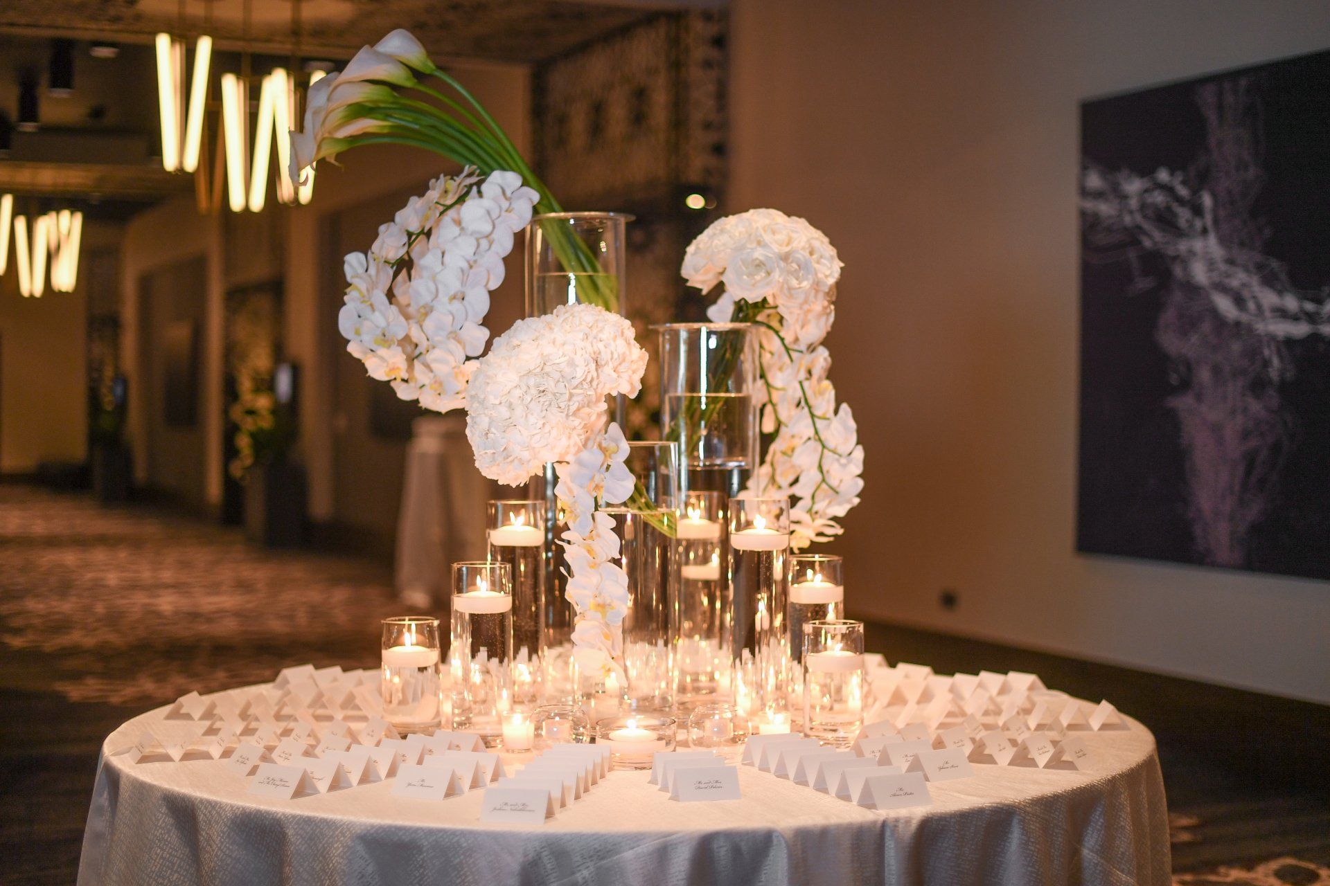 A round table with white flowers and candles on it.