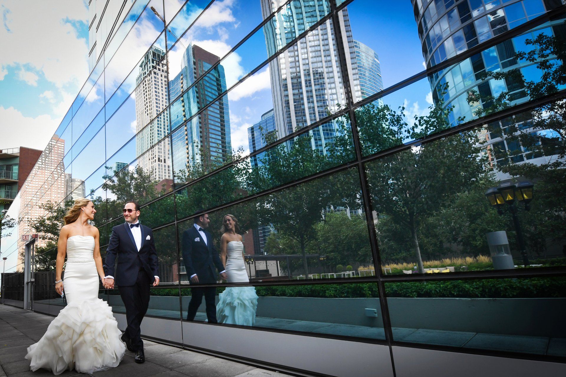 A bride and groom are walking in front of a building.