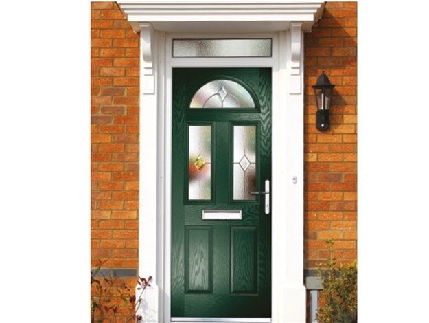 A green door is on a brick building with a canopy.