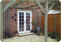 A patio with a pergola and sliding glass doors.