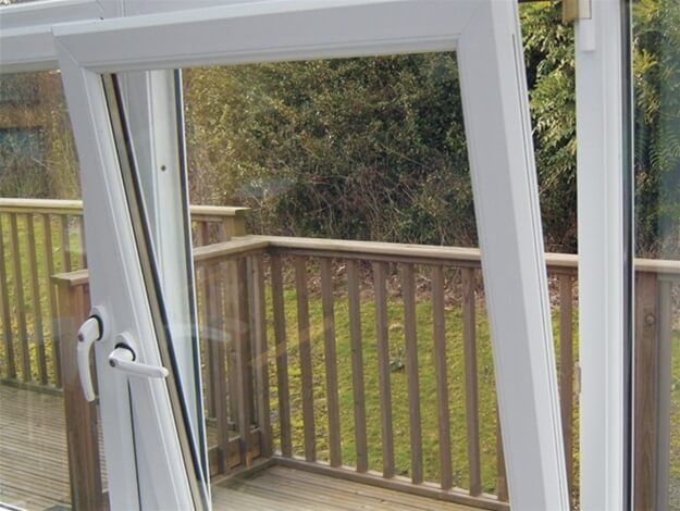 A white sliding glass door is open to a wooden deck.