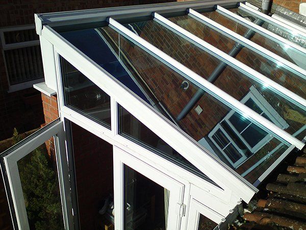 A white conservatory with a clear glass roof