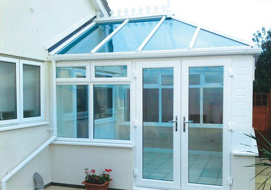 A white house with a glass roof and french doors