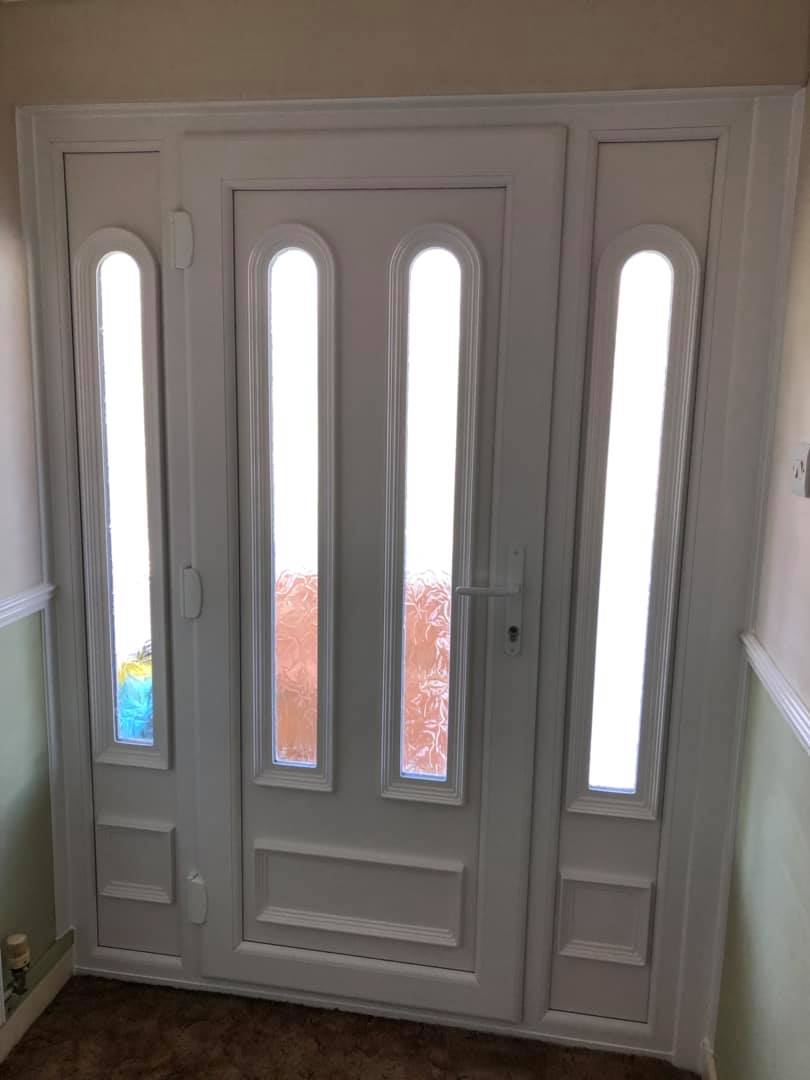 A white door with three windows in a hallway.