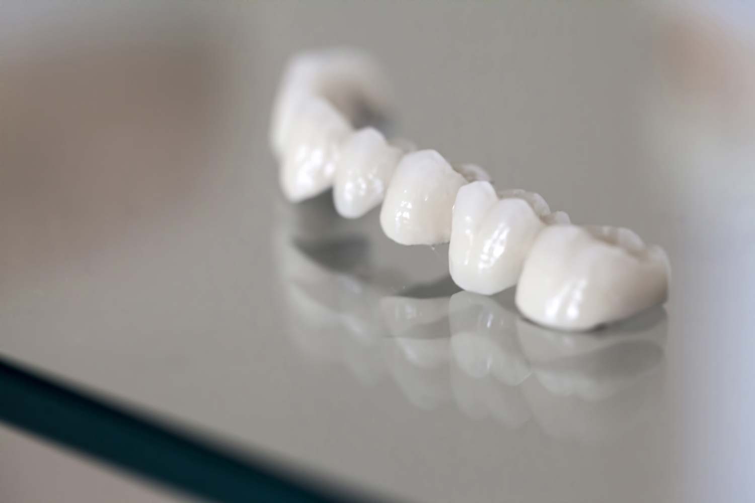 A close up of a dental bridge on a glass table.