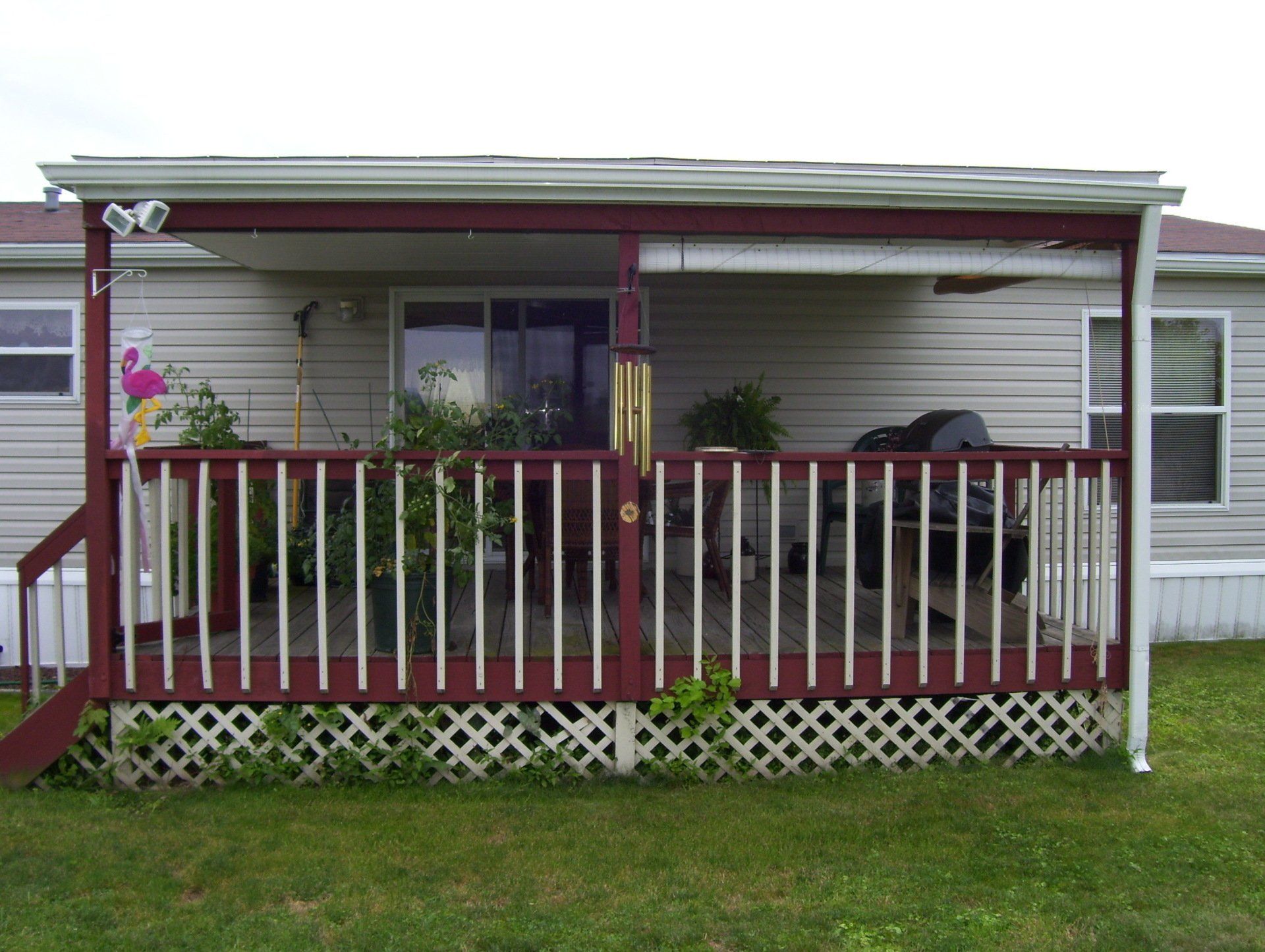A white house with a red porch and a wind chime