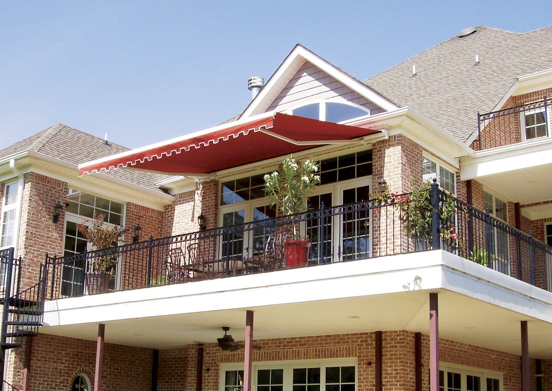 A large brick house with a balcony with a red awning