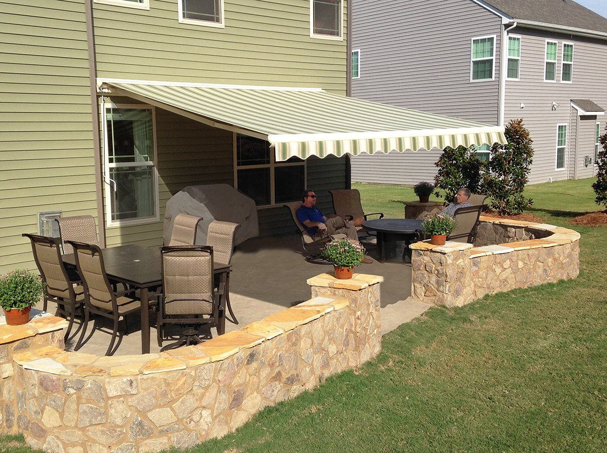 A man sits under an awning on a patio