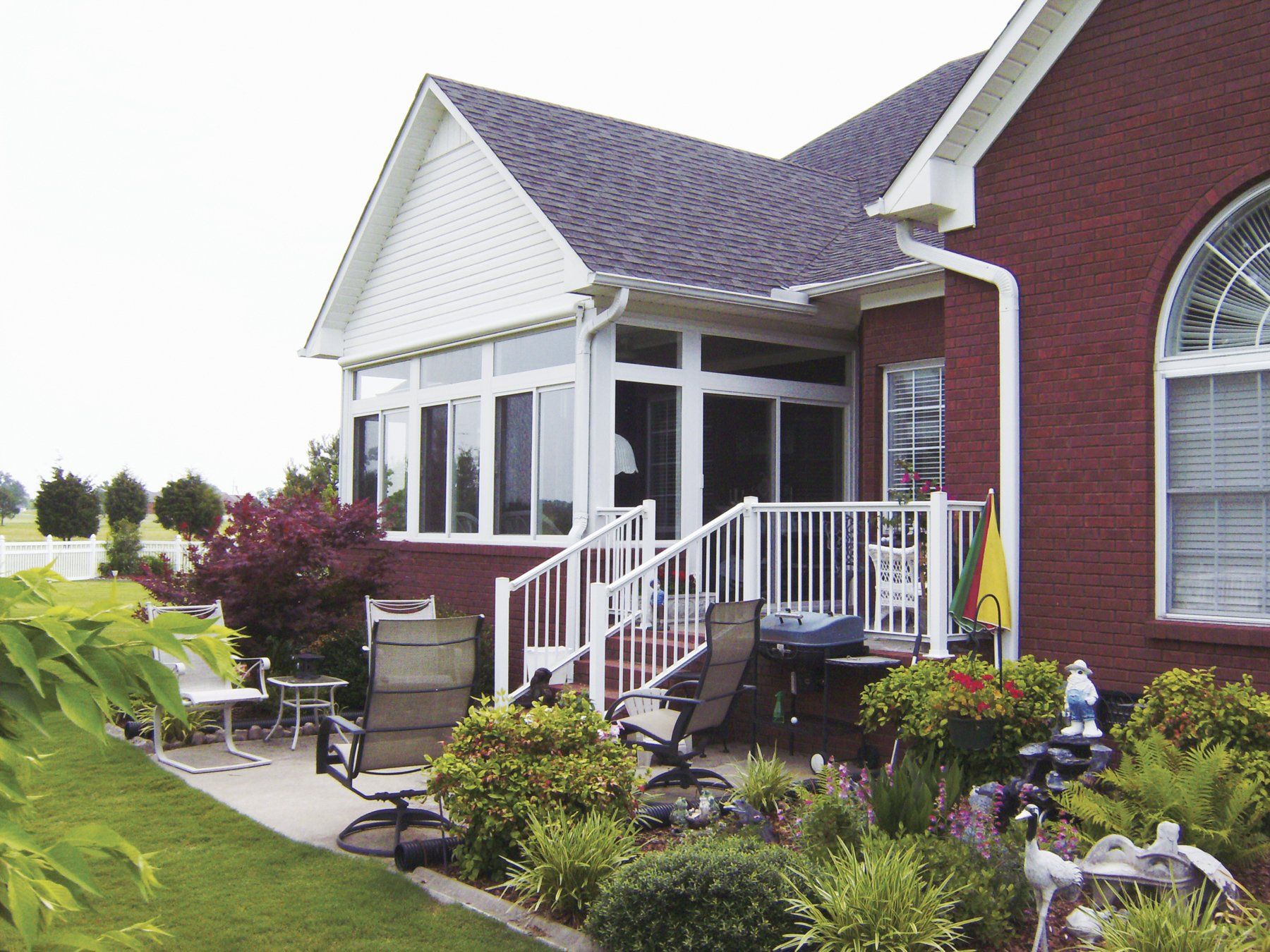 A red brick house with a white porch and stairs