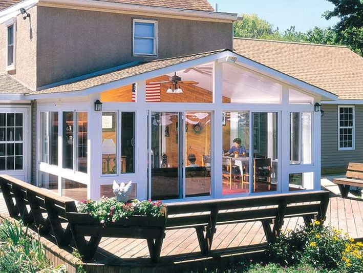 A man sits at a table in the sunroom of a house