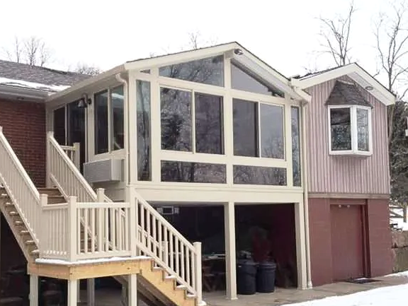 A house with a sunroom and stairs leading up to it.