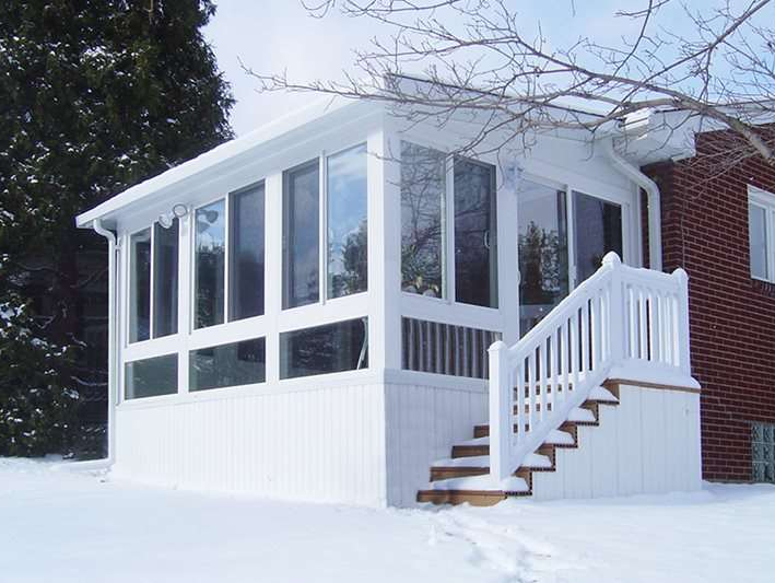 A house with a white porch and stairs in the snow
