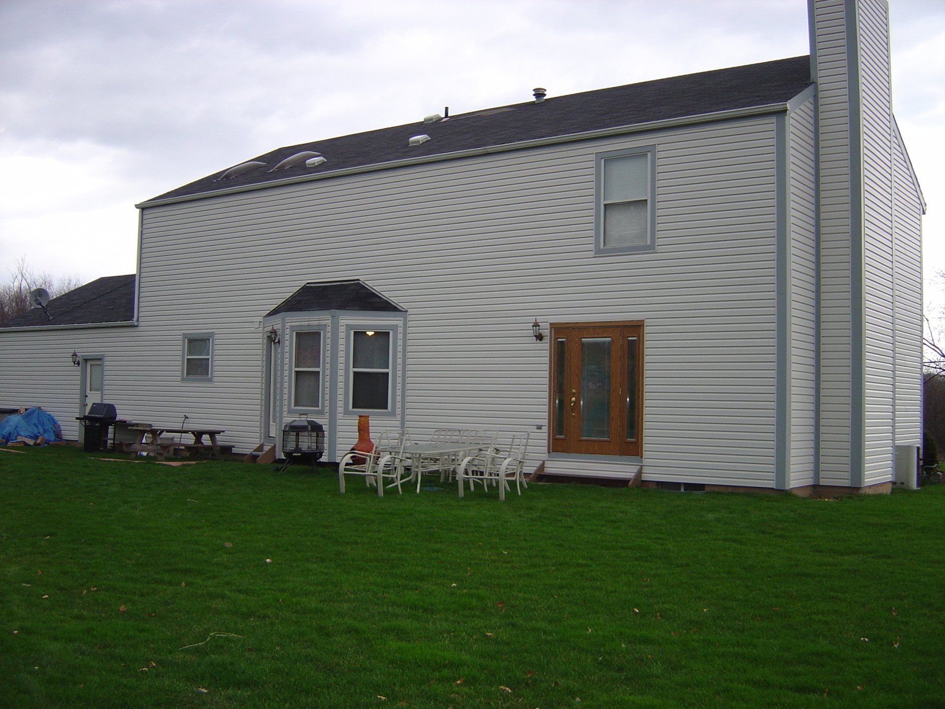 A white house with a brown door sits on a lush green lawn