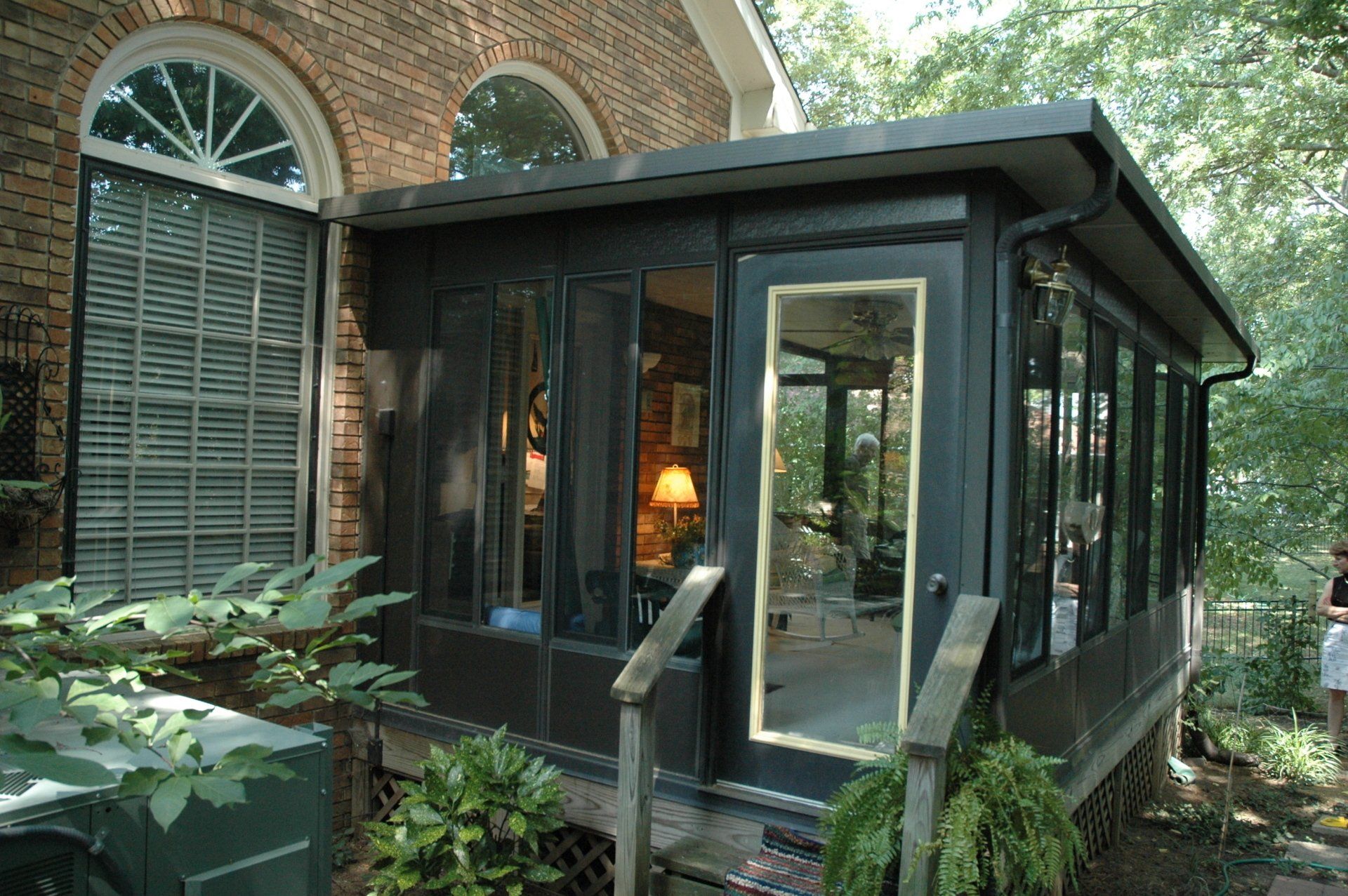 A screened in porch with a brick house in the background