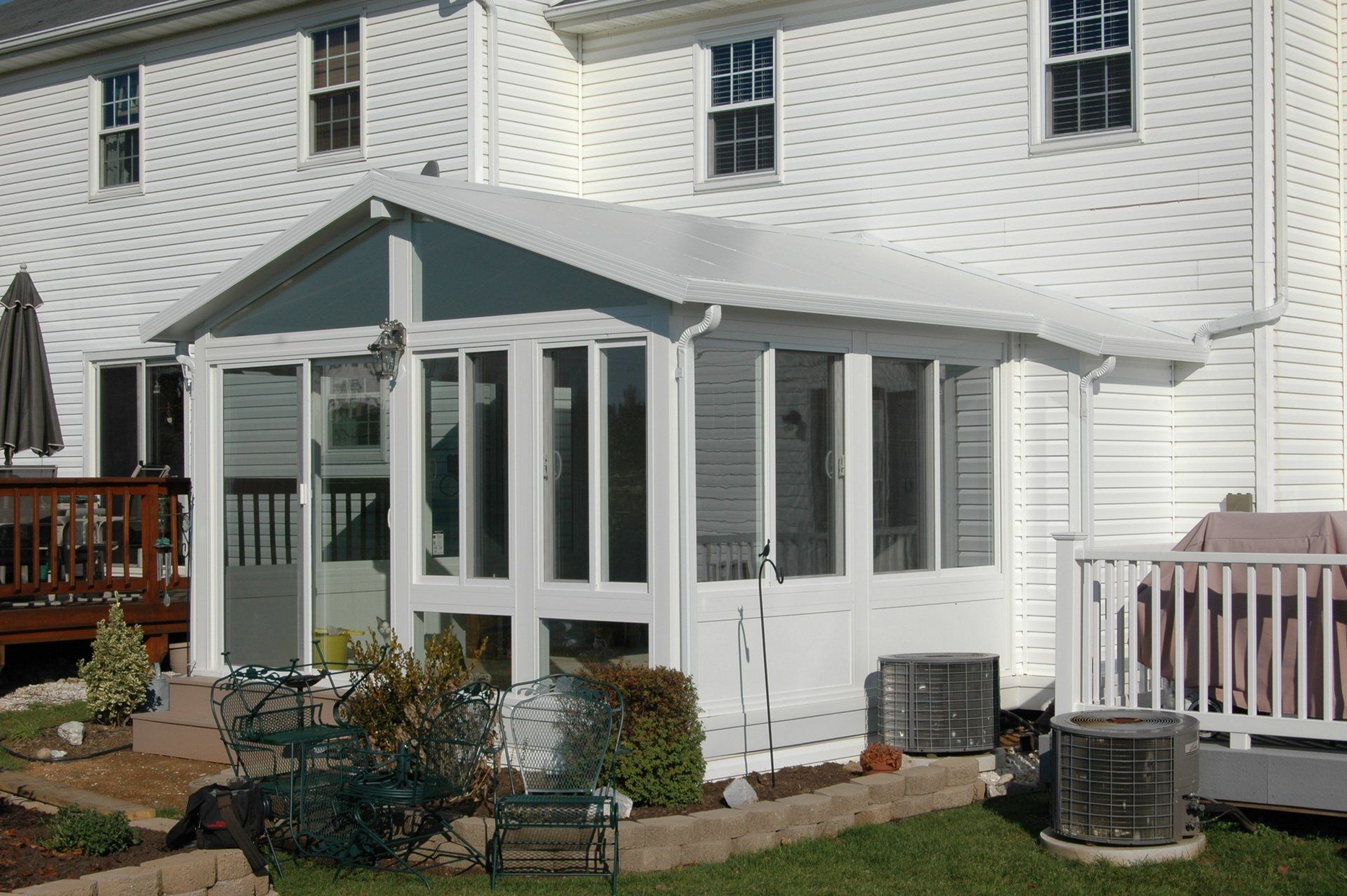 A white house with a screened in porch in the backyard